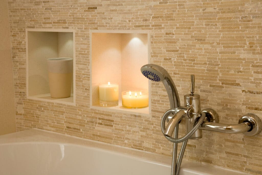 Shower head and taps over a bath with candles